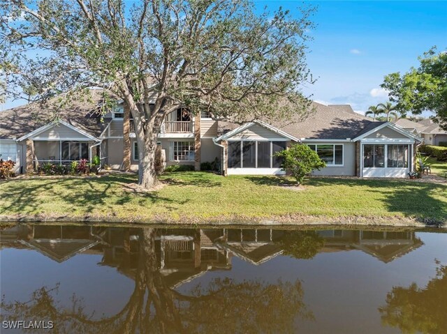 back of house featuring a lawn, a sunroom, and a water view