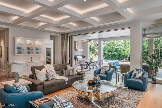 living room with beam ceiling, ceiling fan, coffered ceiling, and light hardwood / wood-style floors