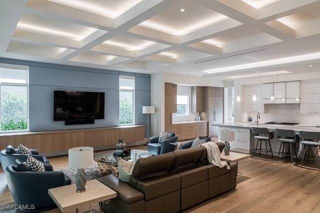 living room featuring coffered ceiling, plenty of natural light, beam ceiling, and light hardwood / wood-style flooring