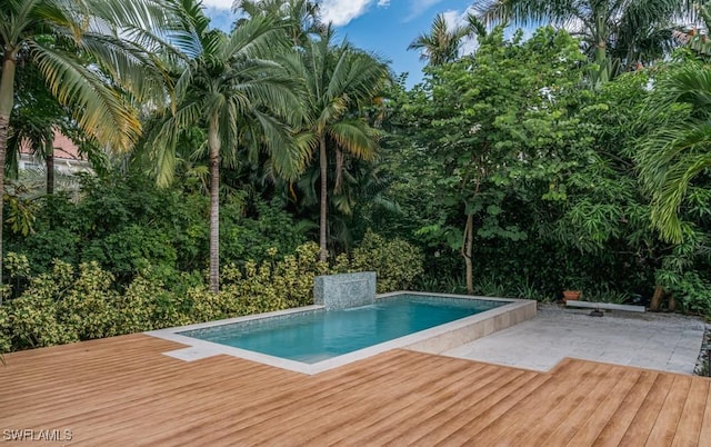 view of swimming pool featuring a wooden deck, pool water feature, and a patio