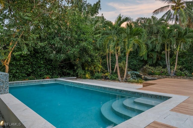 pool at dusk with a wooden deck