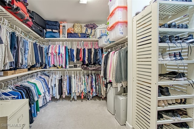 walk in closet with light carpet