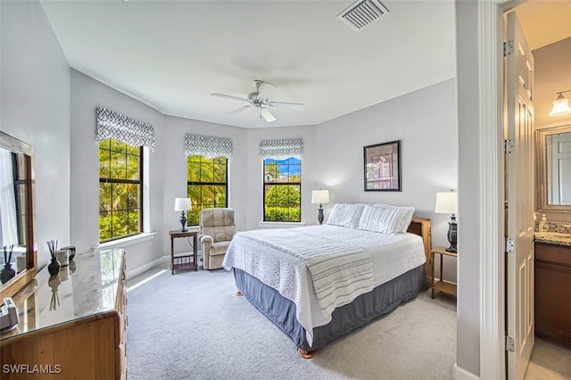 bedroom with light carpet, connected bathroom, and ceiling fan