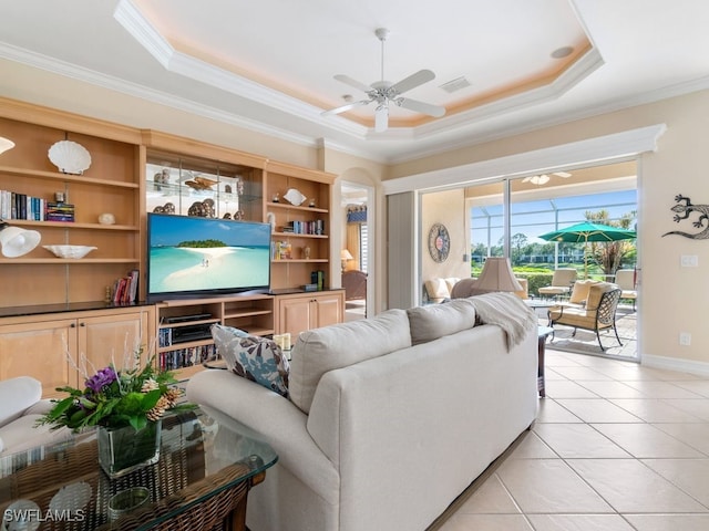 living room with a tray ceiling, ceiling fan, crown molding, and light tile patterned flooring