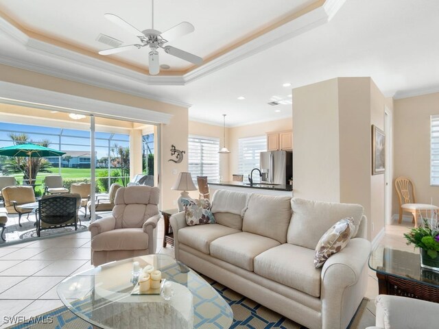 tiled living room featuring ceiling fan, a raised ceiling, ornamental molding, and sink