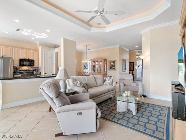 living room featuring light tile patterned floors, ceiling fan with notable chandelier, a tray ceiling, and ornamental molding