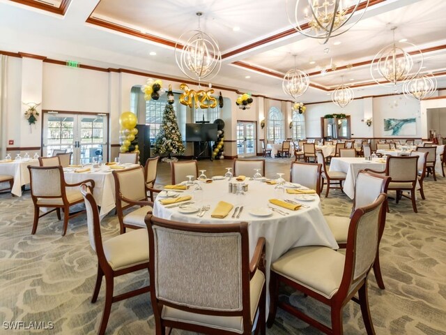 dining space featuring an inviting chandelier, a raised ceiling, ornamental molding, and french doors