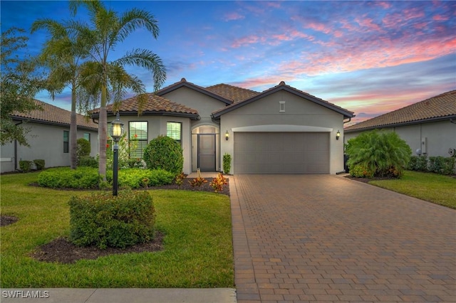 mediterranean / spanish-style house featuring a garage and a yard