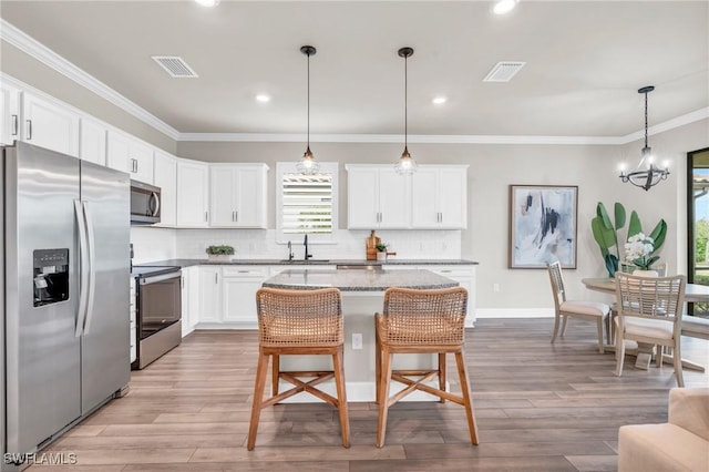 kitchen with a kitchen island, pendant lighting, a breakfast bar area, stainless steel appliances, and white cabinets