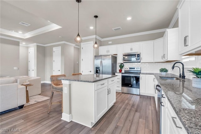 kitchen featuring white cabinets, a center island, stainless steel appliances, tasteful backsplash, and sink