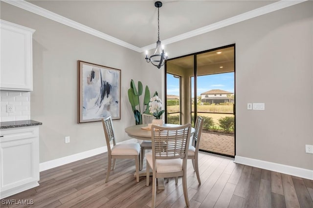 dining room with hardwood / wood-style flooring, ornamental molding, and a notable chandelier