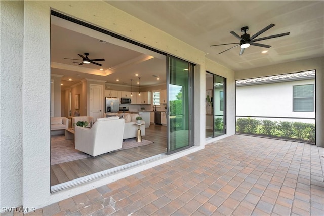 unfurnished sunroom featuring ceiling fan and a tray ceiling