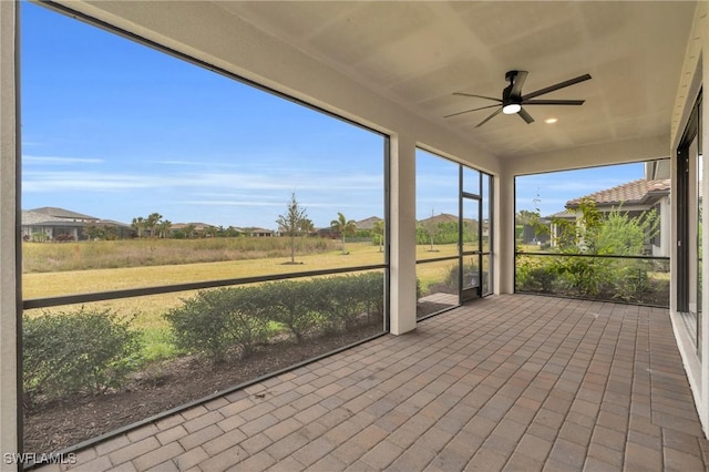 unfurnished sunroom featuring ceiling fan