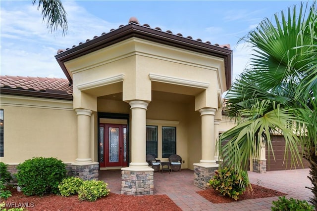 view of exterior entry featuring stucco siding, a porch, and a tiled roof