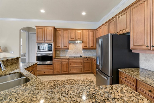 kitchen featuring stainless steel appliances, backsplash, crown molding, light stone counters, and sink