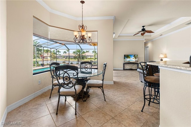 dining area featuring ceiling fan with notable chandelier, light tile patterned floors, a tray ceiling, and ornamental molding