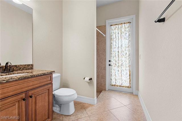 bathroom with toilet, vanity, tile patterned floors, and walk in shower