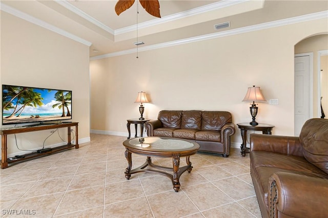 tiled living room with ceiling fan, a tray ceiling, and ornamental molding