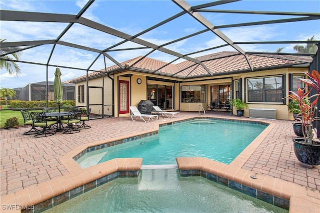 view of pool featuring glass enclosure, a patio area, and an in ground hot tub