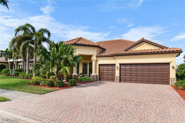 mediterranean / spanish-style house featuring stone siding, stucco siding, decorative driveway, and a garage