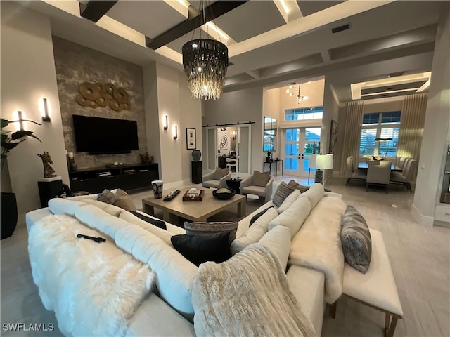 living room featuring a barn door, french doors, a high ceiling, and an inviting chandelier