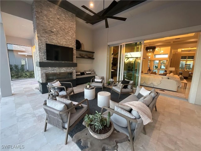 living room with a fireplace, beam ceiling, ceiling fan, and a high ceiling