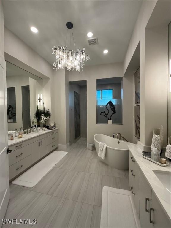 bathroom with tile patterned flooring, vanity, a bath, and a chandelier