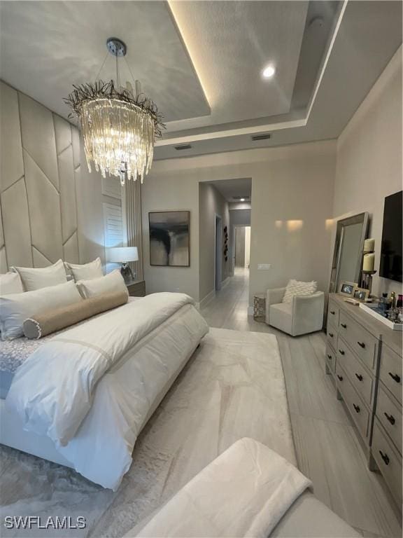 bedroom with a chandelier, light hardwood / wood-style flooring, and a raised ceiling