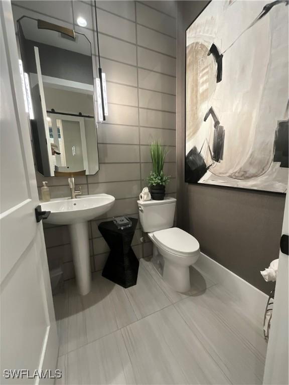 bathroom with sink, tile walls, and toilet