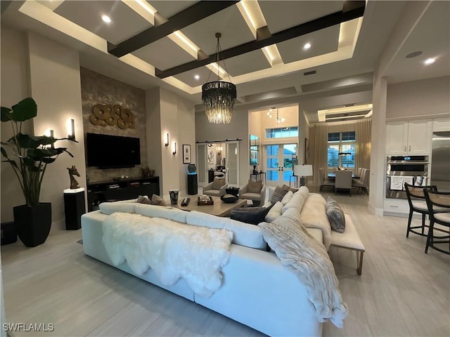 living room with a towering ceiling, light hardwood / wood-style floors, and a notable chandelier