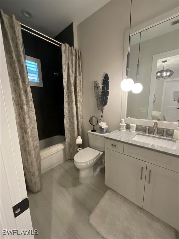 full bathroom featuring shower / tub combo, vanity, an inviting chandelier, and toilet