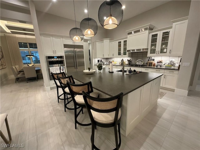 kitchen with white cabinetry, a center island with sink, decorative light fixtures, and appliances with stainless steel finishes