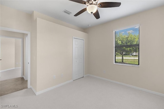 unfurnished bedroom with ceiling fan, light colored carpet, and a closet