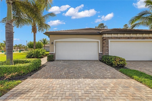 exterior space with stone siding, decorative driveway, an attached garage, and stucco siding