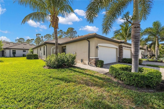 view of side of property featuring a garage, a yard, decorative driveway, and stucco siding