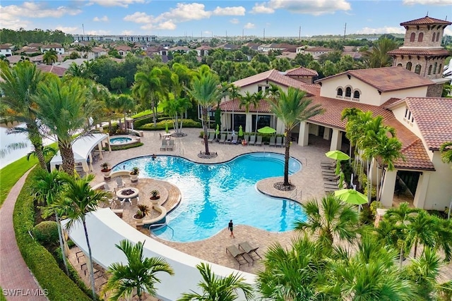 pool with a patio area and a hot tub