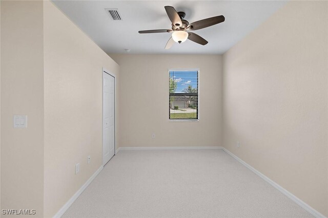 empty room with baseboards, visible vents, ceiling fan, and light colored carpet