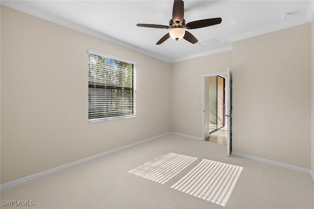 empty room with baseboards, light colored carpet, a ceiling fan, and ornamental molding
