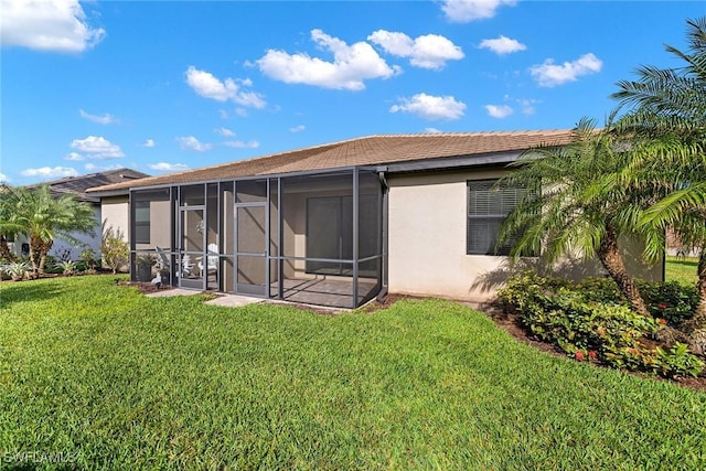 back of property featuring a lawn, a sunroom, and stucco siding