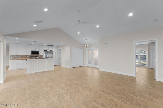 unfurnished living room with ceiling fan with notable chandelier and high vaulted ceiling