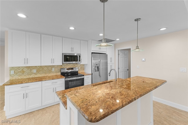 kitchen with white cabinets, stainless steel appliances, hanging light fixtures, and a kitchen island with sink