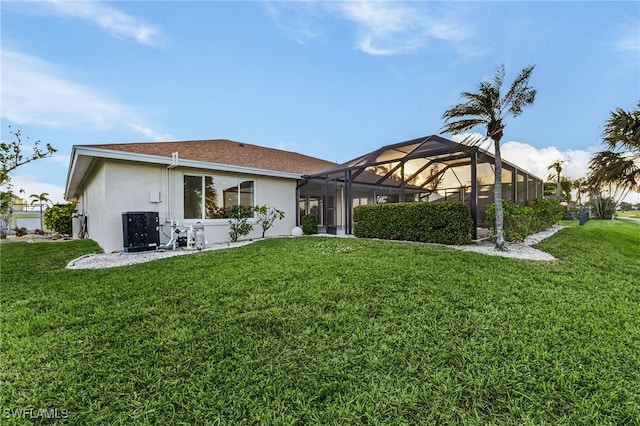 back of property with a yard, glass enclosure, and central AC unit