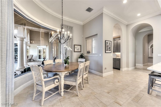 dining room with decorative columns, crown molding, and a notable chandelier