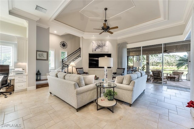 living room featuring ceiling fan, ornamental molding, and a tray ceiling