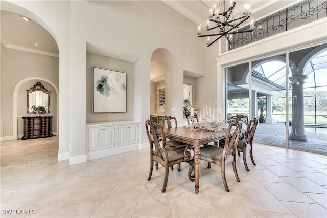 dining space featuring a high ceiling, crown molding, a wealth of natural light, and an inviting chandelier