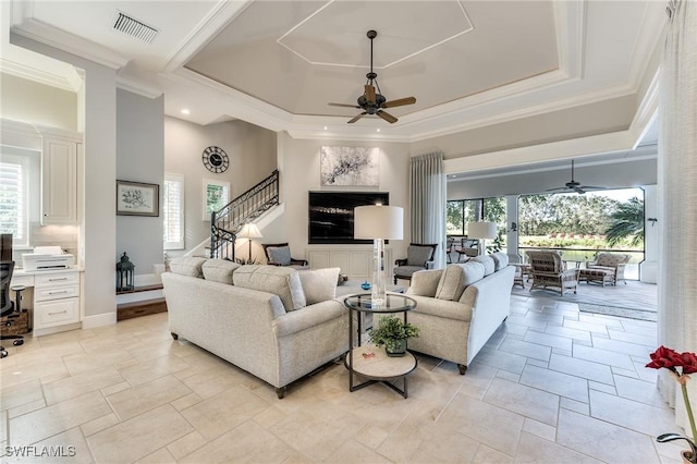 living room featuring a tray ceiling, ceiling fan, and ornamental molding