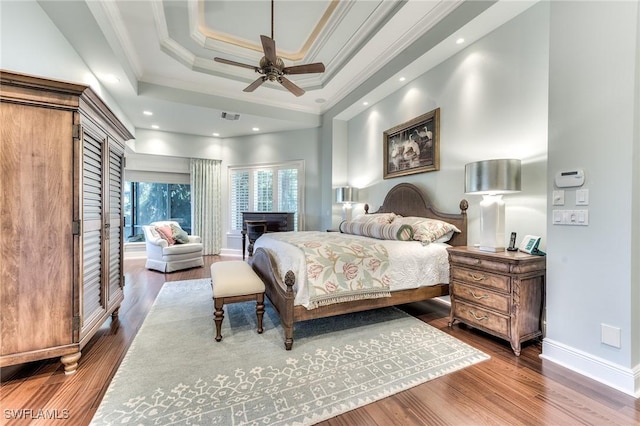 bedroom featuring ceiling fan, a raised ceiling, wood-type flooring, and crown molding