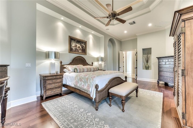 bedroom with ceiling fan, a raised ceiling, ornamental molding, and dark wood-type flooring