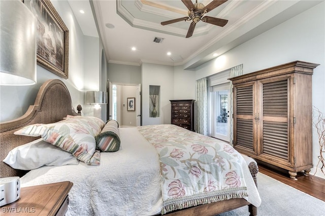 bedroom with ceiling fan, access to exterior, ornamental molding, a tray ceiling, and wood-type flooring