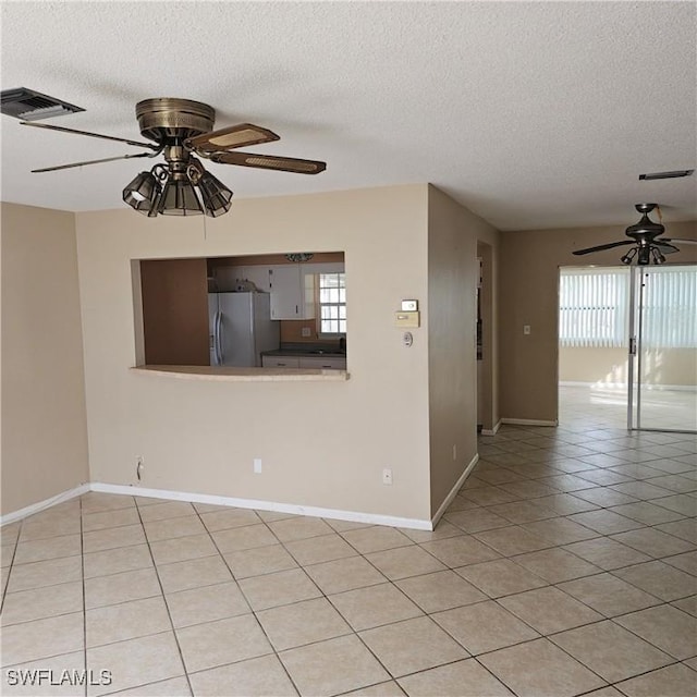 tiled empty room with ceiling fan and a textured ceiling